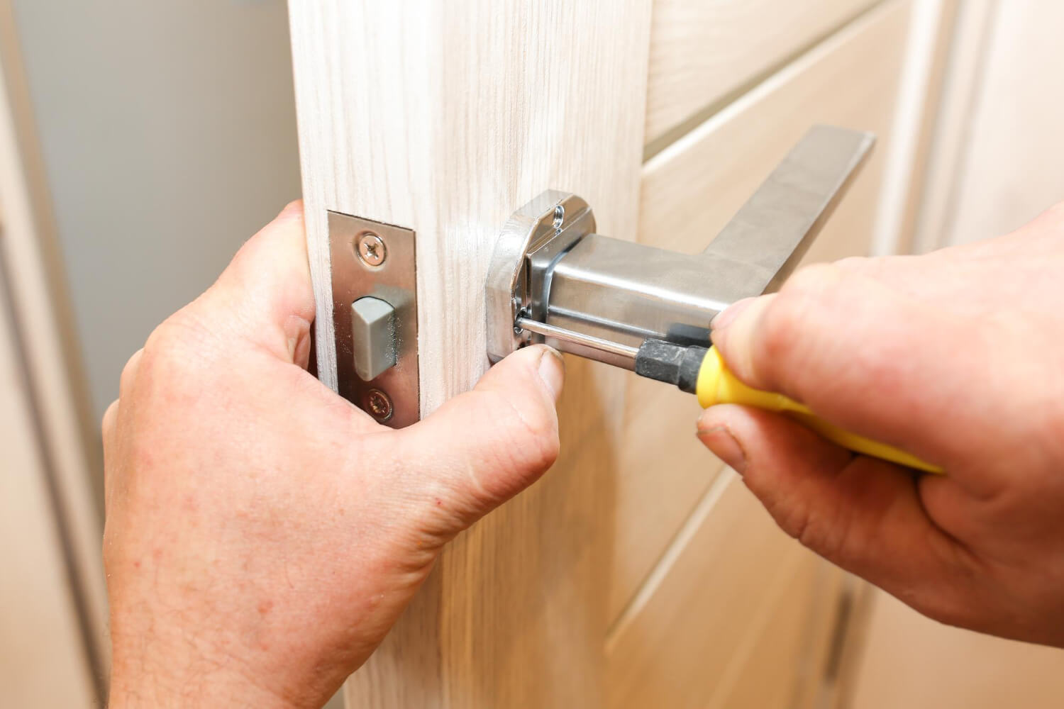 handyman installing door handle and lock on wooden internal door